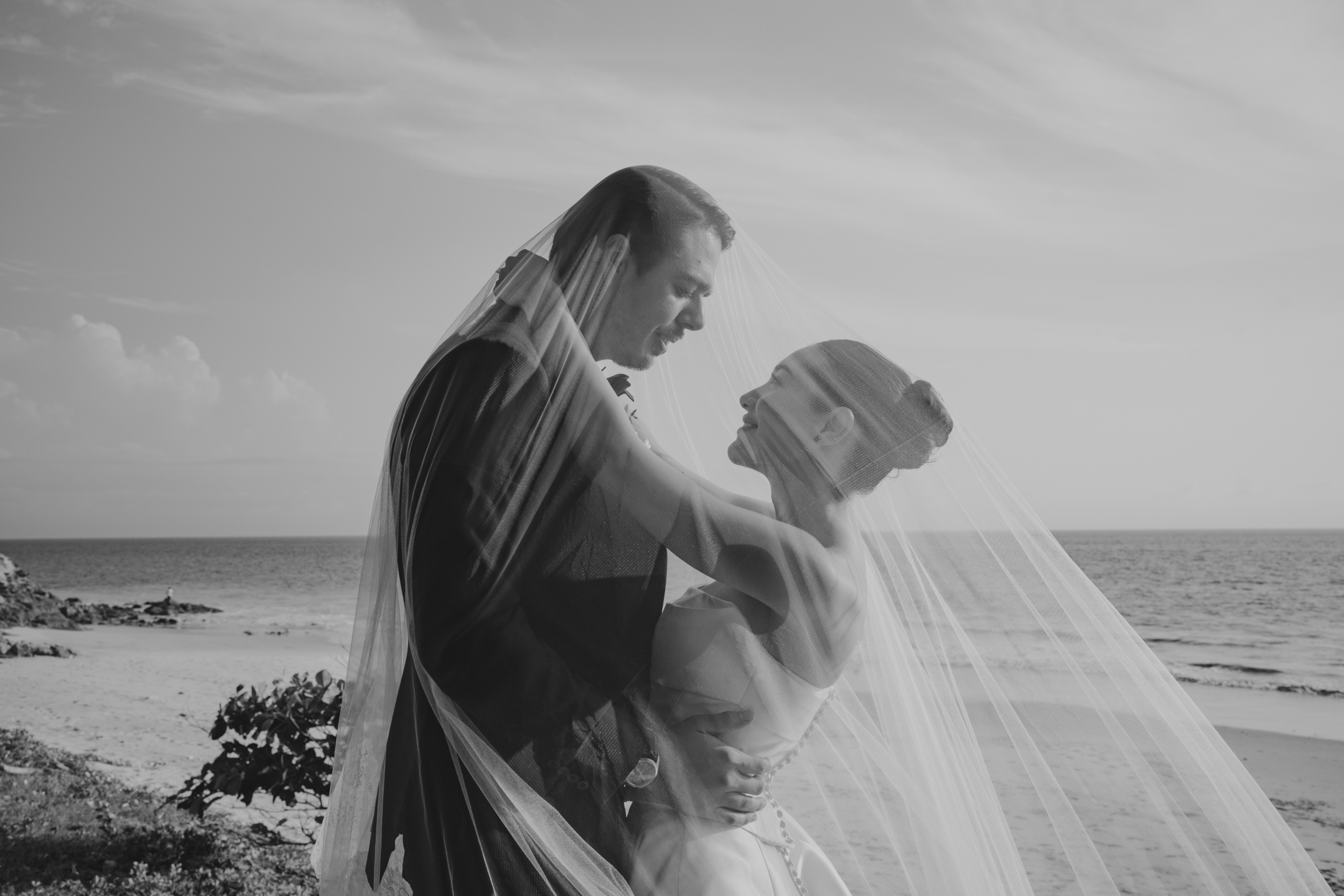 Bride and groom embrace under the veil on a Punta de Mita beach, black and white