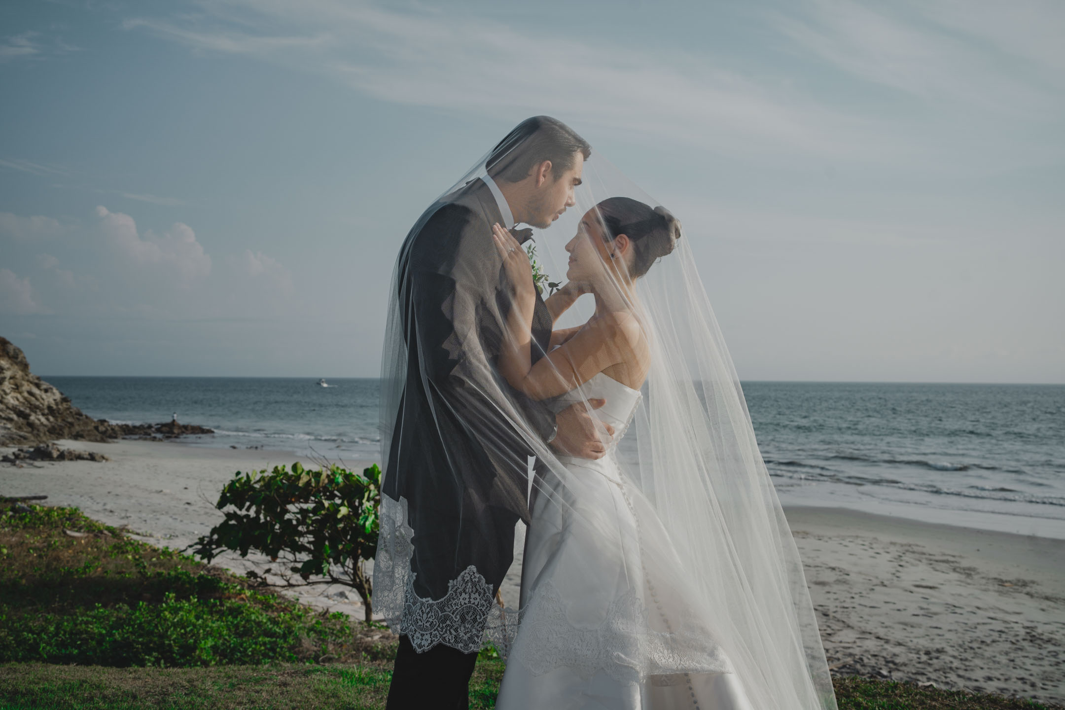 Bride and groom embrace under the veil on a Punta de Mita beach