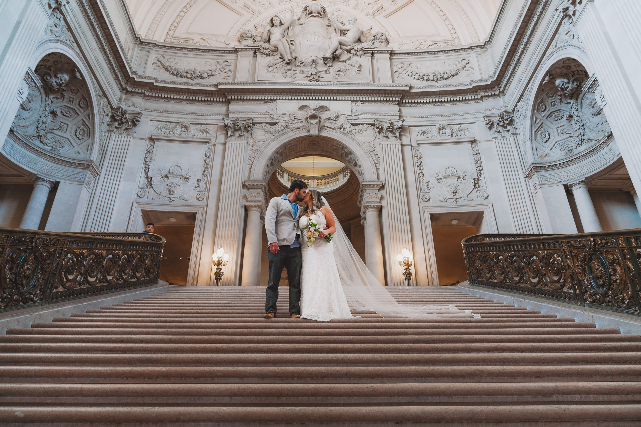 Bride and groom share a kiss on a grand staircase
