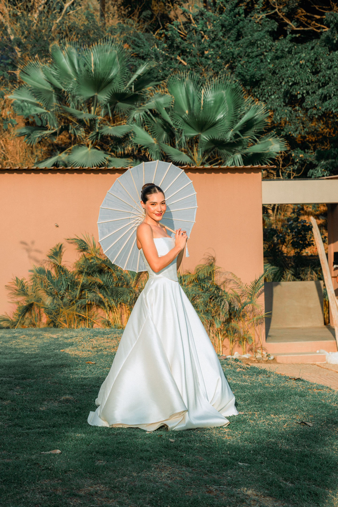 Bride with parasol in a tropical garden